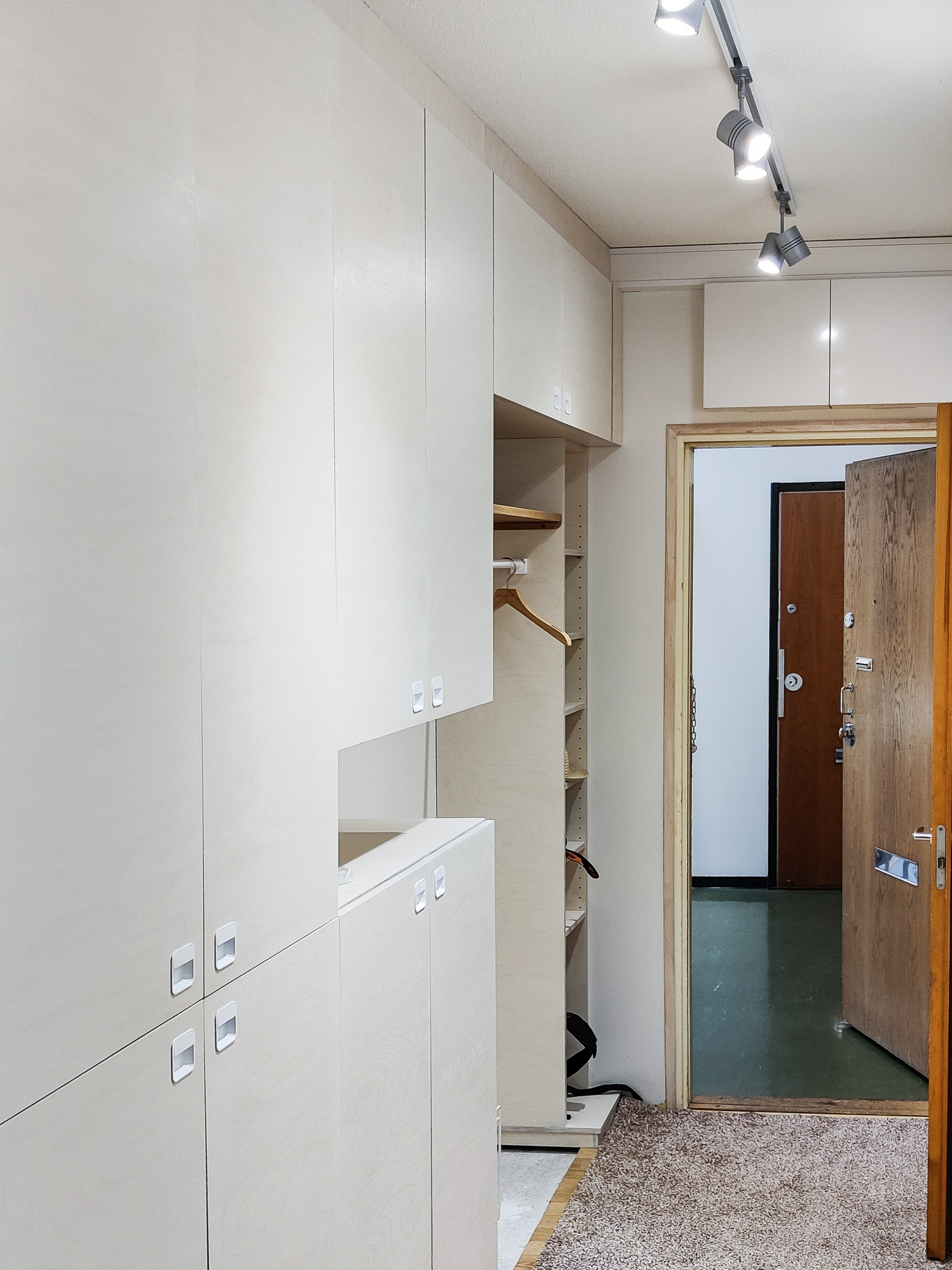 Kirjahylly koivusta maalattuna. Alhaalla kehysovelliset kaapit, yläpuolella tila tv:lle ja korkeussäädettävät hyllylevyt.