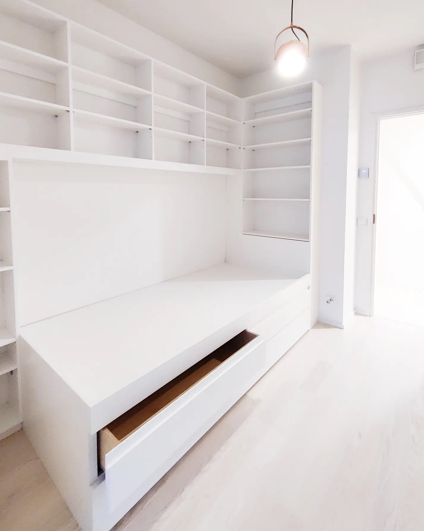 Korotettu sänky, jonka alla lisävuode ja säilytyslaatikot. Sängyn yläpuolella ja molemmissa päädyissä kirjahylly.