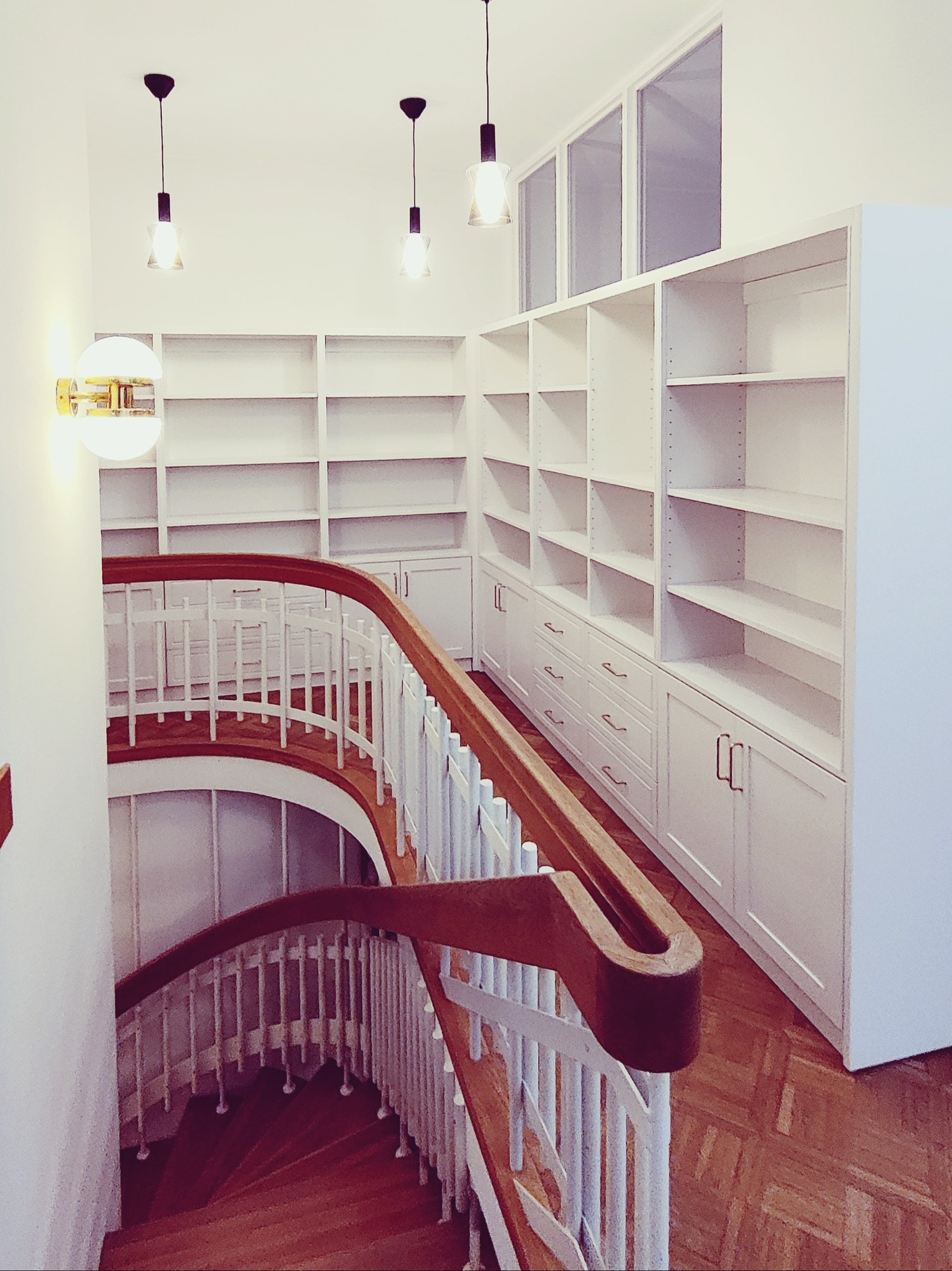 Kirjahylly rappukäytävään alakaapeilla ja vetolaatikoilla. Materiaalina massiivikoivu. 