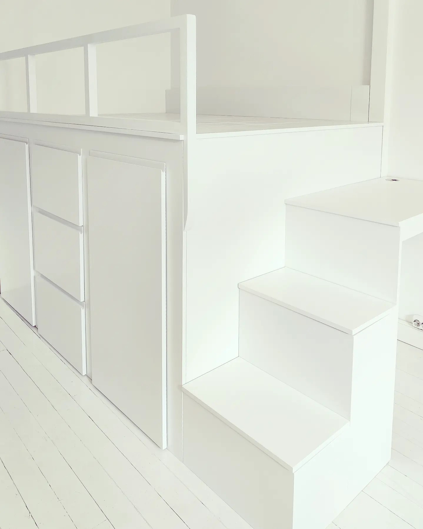 Korotettu sänky vaatetangollisilla vetolaatikoilla ja kirjahyllyllä