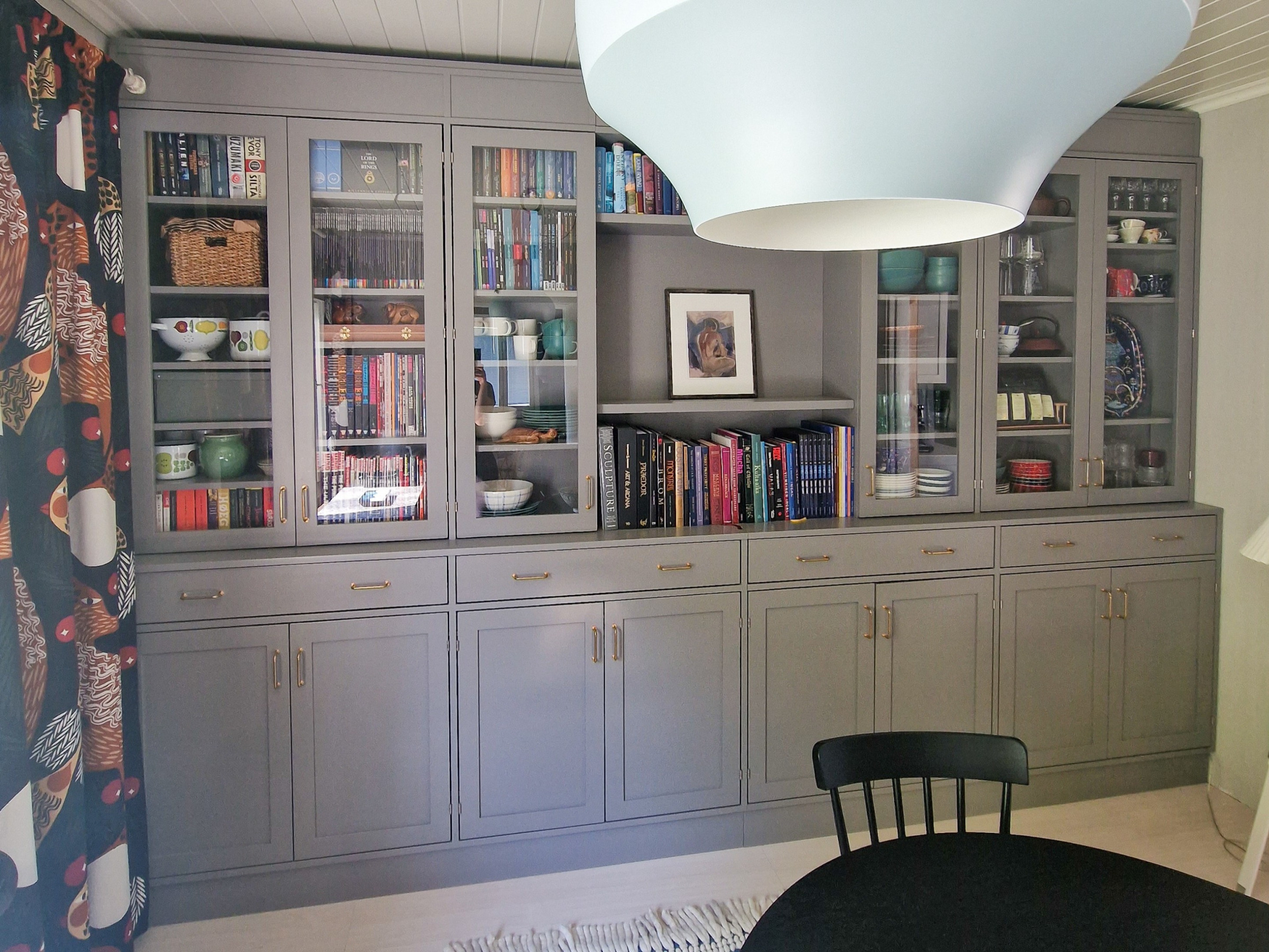 Build-in kirjahylly lasiovilla ja vetolaatikoilla sekä alakaapeilla.