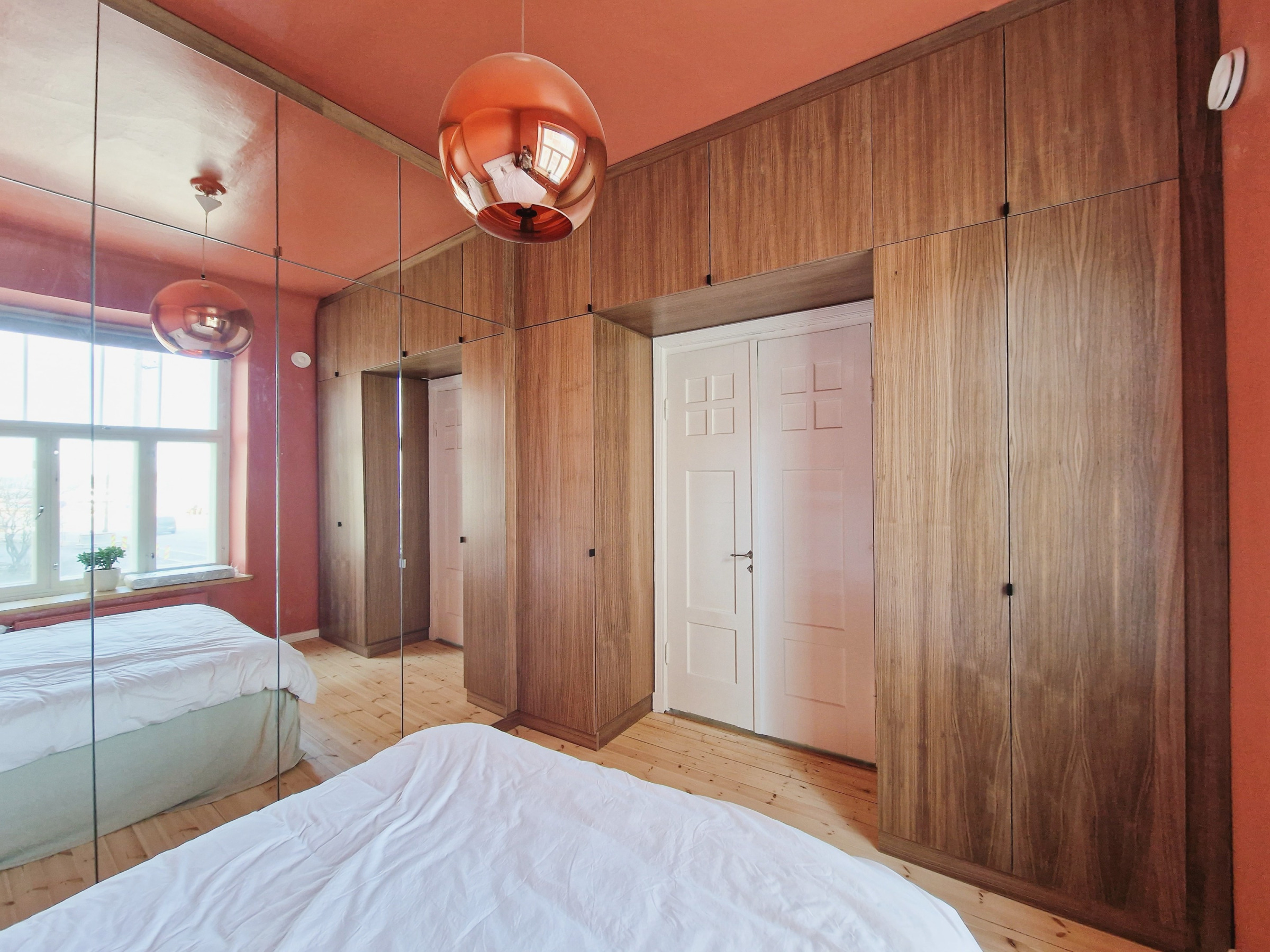 Build-in kirjahylly männystä, valkoiseksi maalattuna. Keskellä sohvatila. Ylhäällä hyllytilaa.